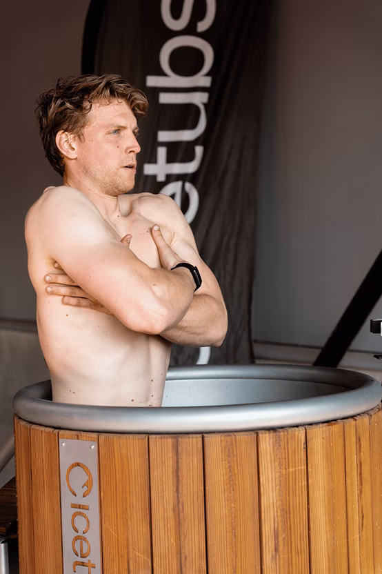 Gespierde man in Icetubs koudwaterbad met gekruiste armen